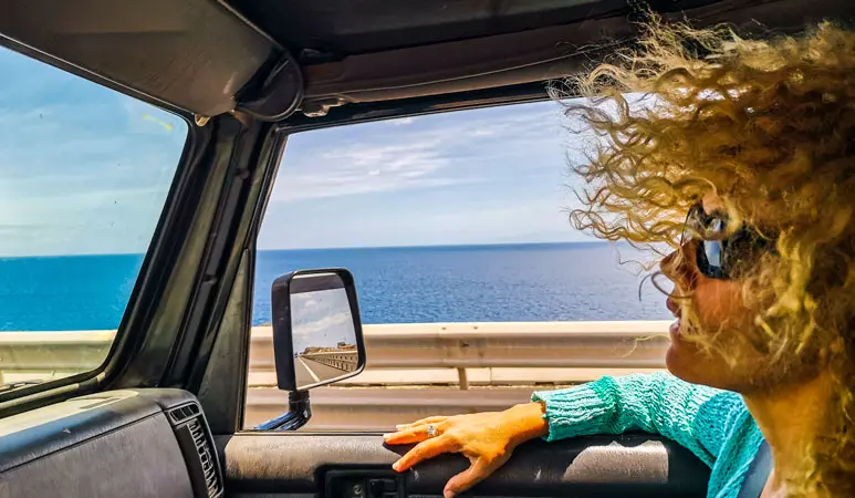 Viajera mirando el mar Mediterráneo por la ventanilla del coche en la carretera de la costa