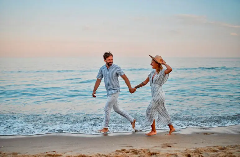 Een stel op het strand dat geniet van een romantische wandeling bij zonsondergang