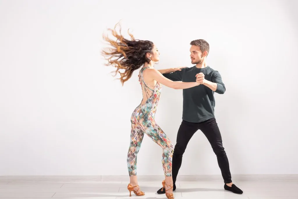 Pareja bailando bachata sobre un fondo claro