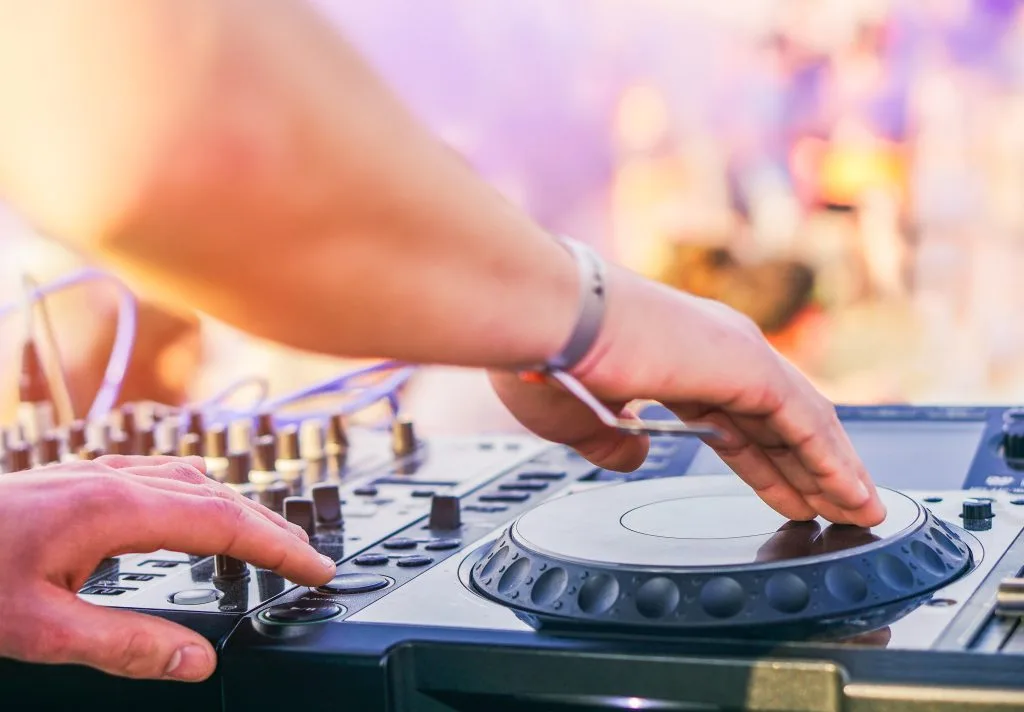 Manos de un dj sobre la mesa de mezclas durante un festival al aire libre