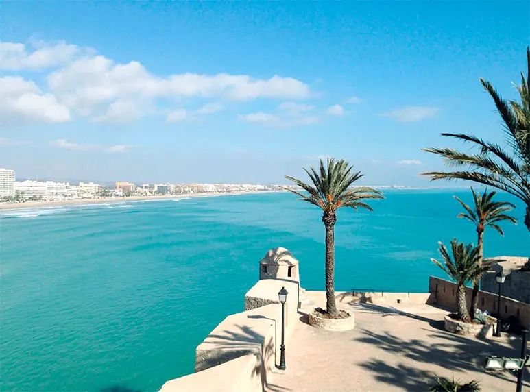 Palmeras junto al Castillo de Peñíscola con vistas al mar Mediterráneo en un día soleado