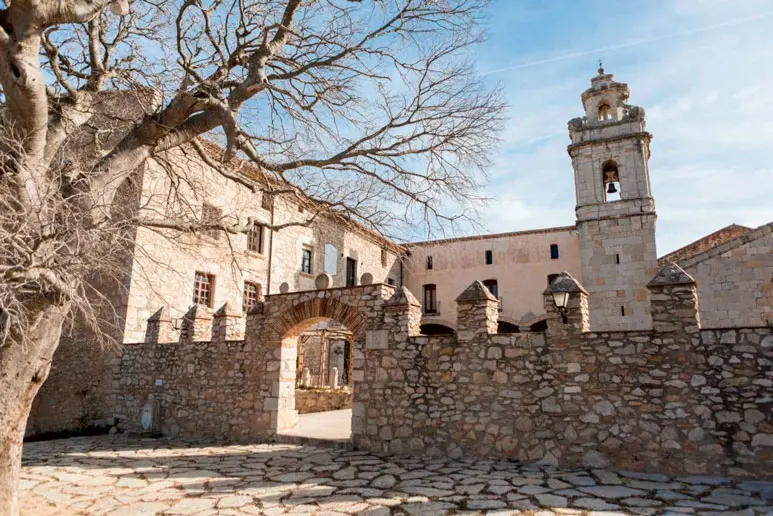 Uitzicht op de kapel Mare de Déu dels Àngels met haar toren en ingang, omgeven door stenen muren