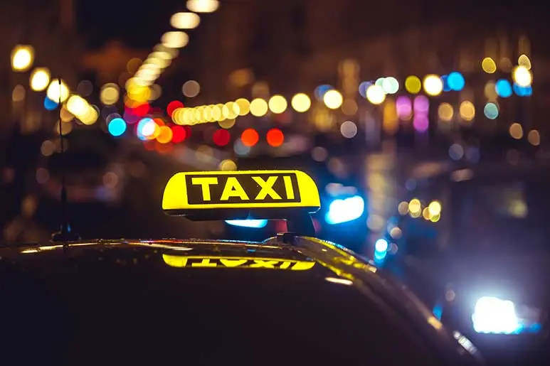 Taxi Oropesa de noche con luces urbanas de fondo